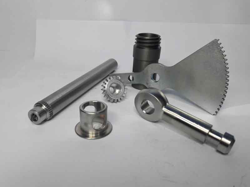 Machined parts family — shaft, bushing, pinion, cam lever, and toothed cam